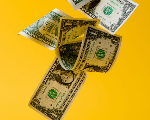 close up view of falling dollar banknotes isolated on yellow